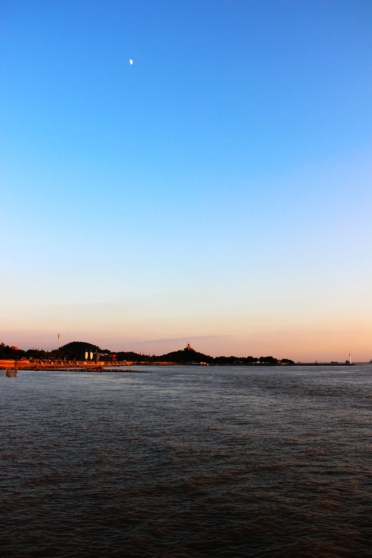 狼山、灯塔、残月、夕阳交相辉映中，形成了一幅独特的画面。