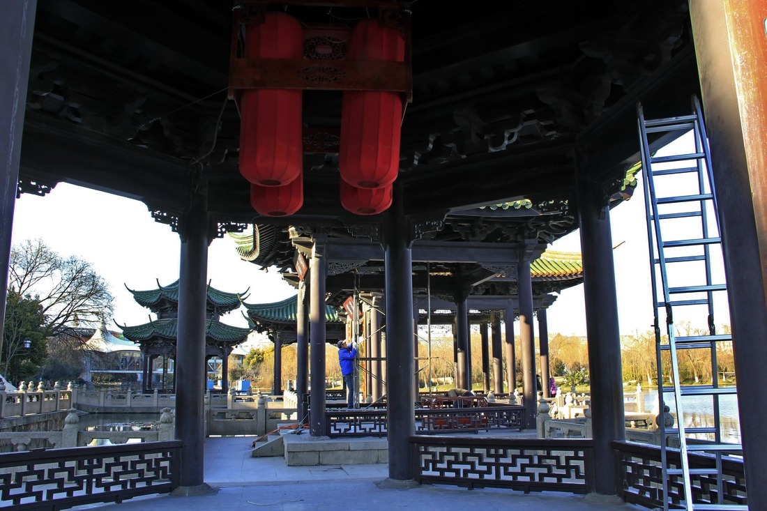 3、	工人在另一座亭内做着挂大红灯笼的前期准备工作。