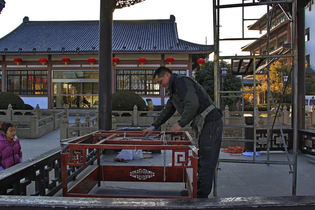 7、	工人给大灯笼架子四个角上部安装上铁链悬挂吊索和吊钓。