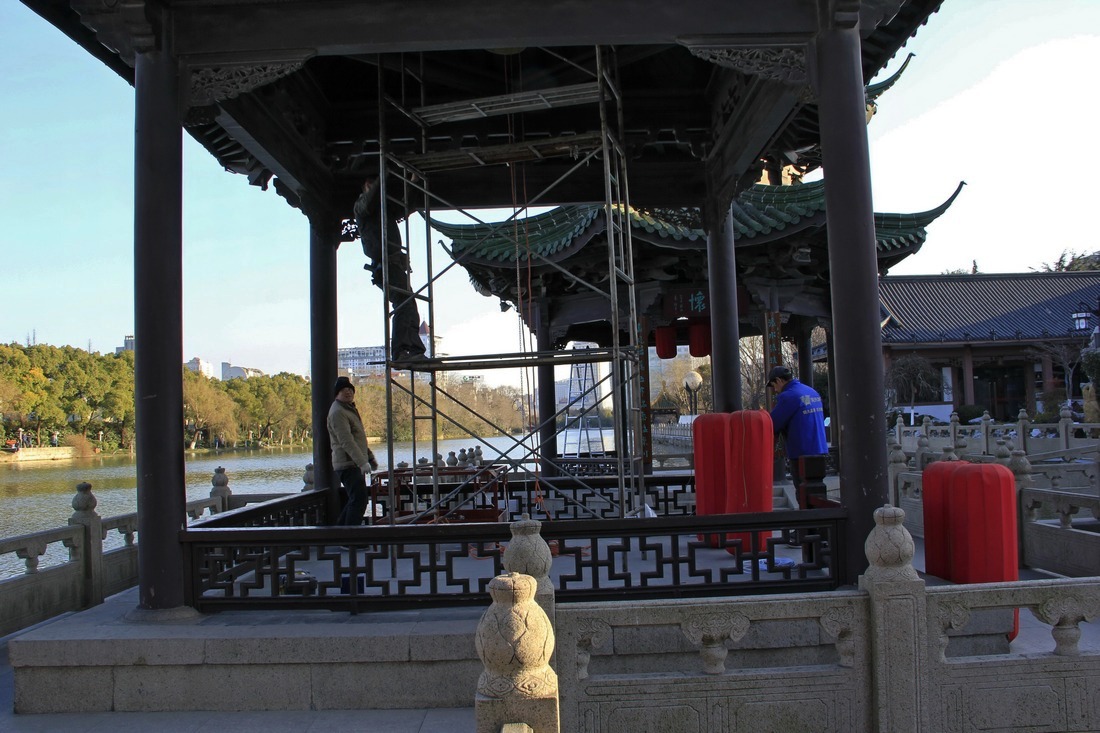 9、	工人有条不紊地做着挂大红灯笼的前期各项工作。