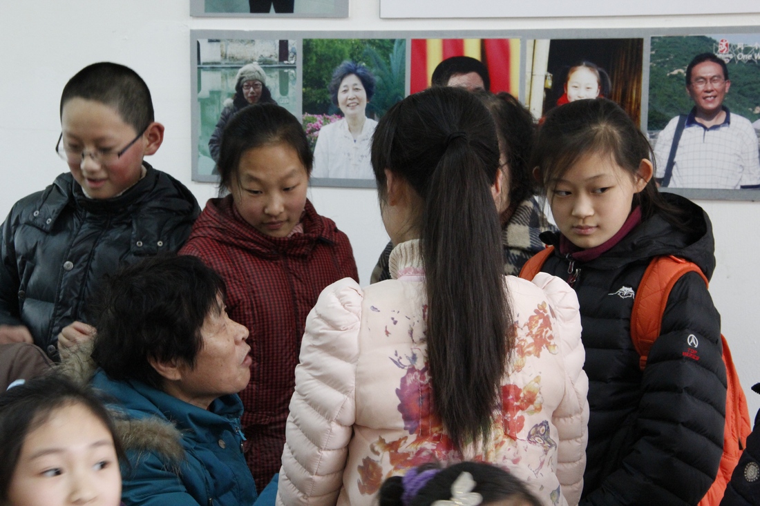 4、	小志愿者听省劳动模范张奶奶讲传统。