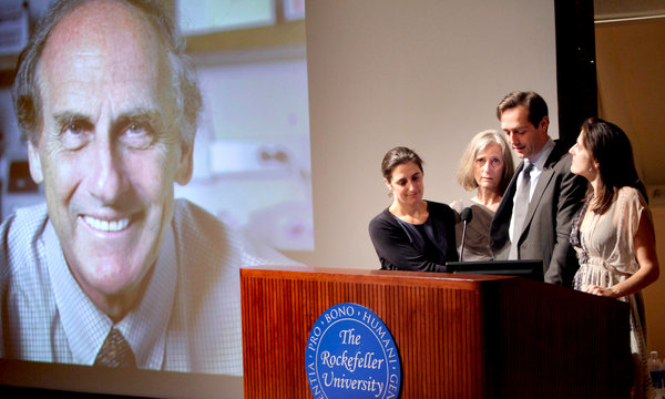 图一：投影显示为 2011 年诺贝尔医学或生理学奖得主拉尔夫 ·  斯坦曼，图为斯坦曼的亲属在其生前任职机构洛克菲勒大学就获奖发表感言（Seth Wenig/Associated Press/nytimes.com）