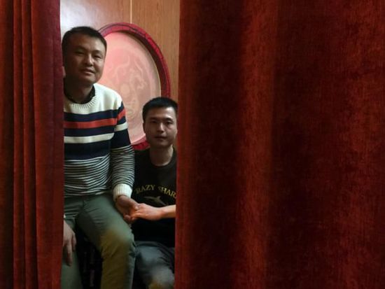 2015年12月22日，湖南省长沙市，坐在沙发上的孙文麟（化名，右）与男朋友手牵手接受记者拍摄。