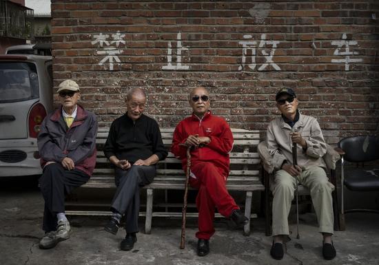 2014年10月2日，北京，几位老人坐在公寓外的长椅上。/视觉中国
