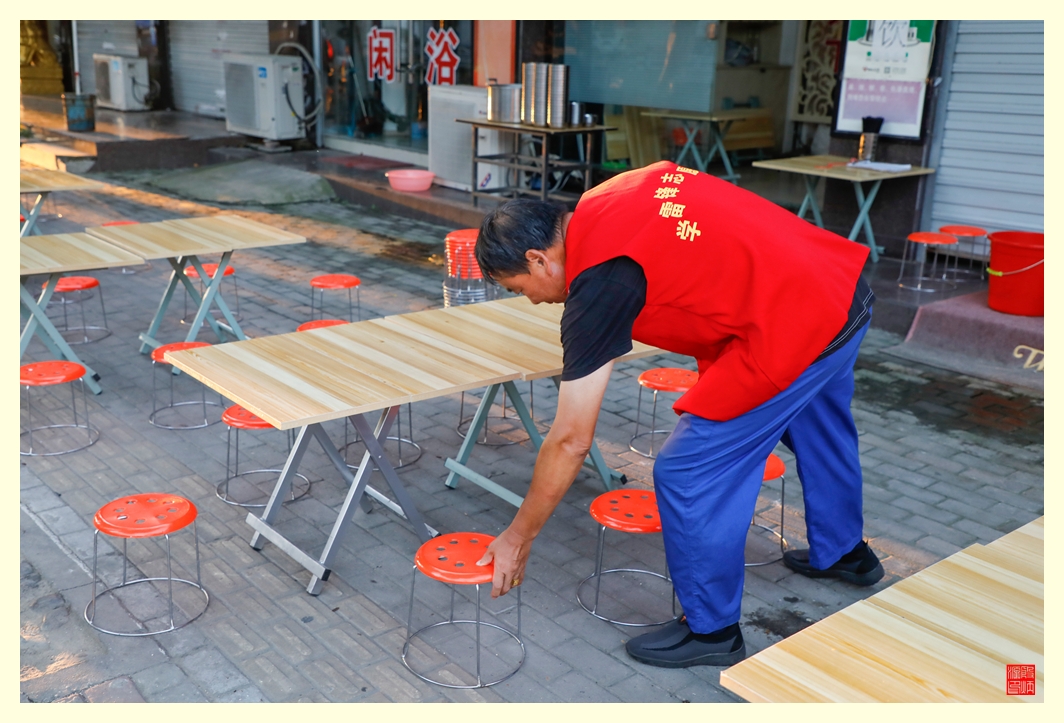 志愿者在摆放小凳子，准备迎接前来就餐的人们。