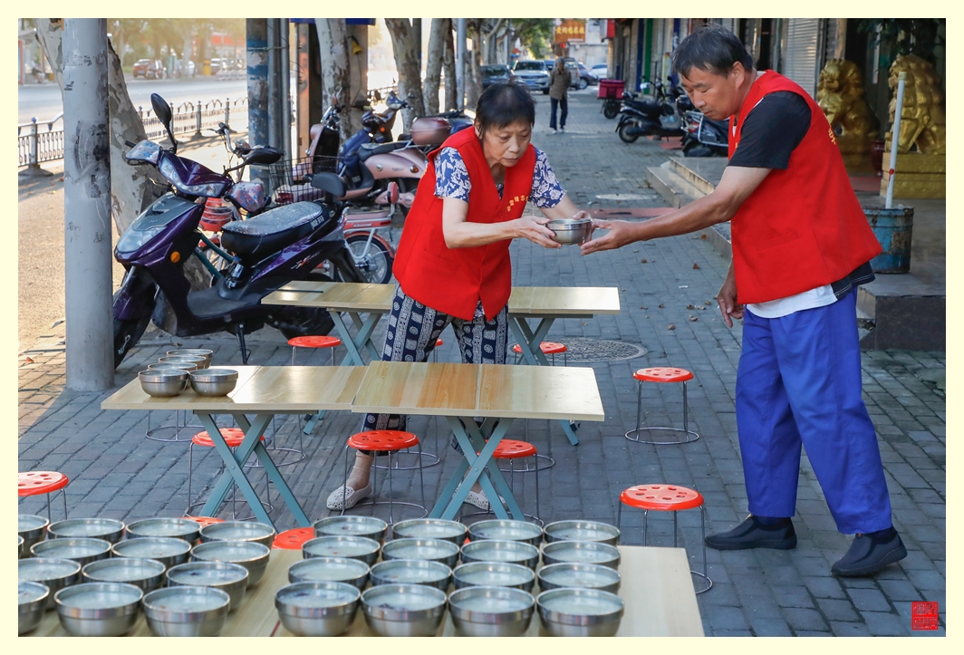 志愿者开始把粥碗摆放在小桌子上。