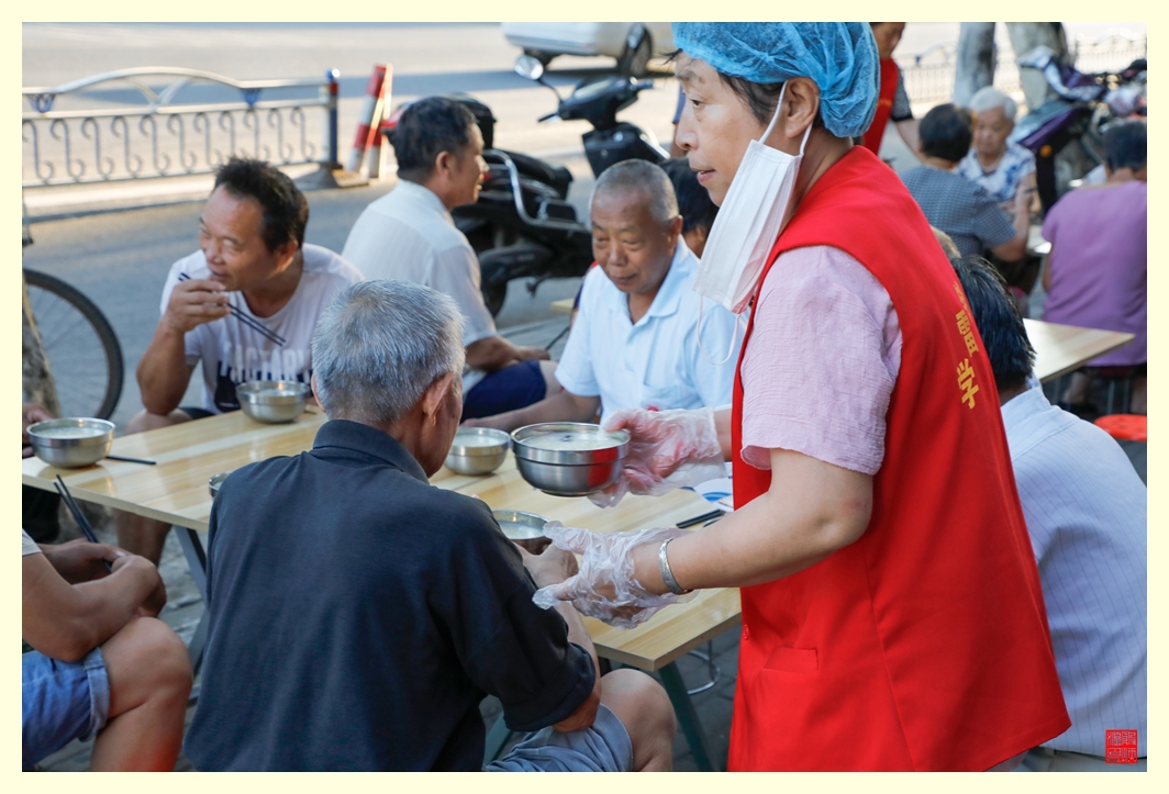 志愿者把爱心粥端给老人。